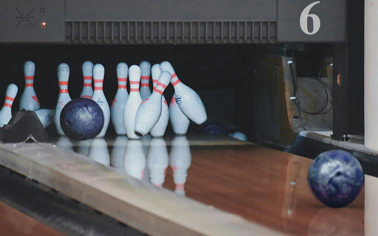 A bowling lane with a bowling ball and pins. 