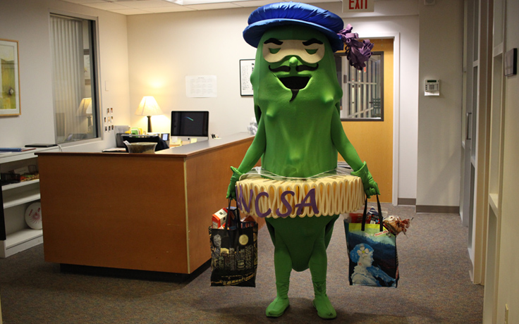 The UNCSA Pickle mascot with bags of donations for the Pickle Pantry