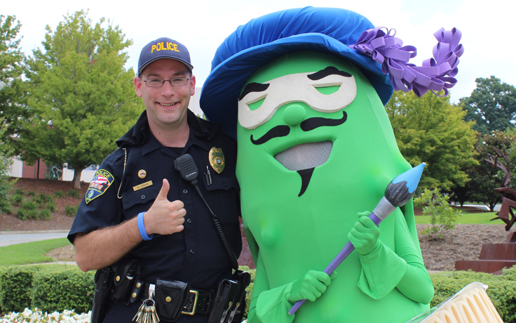 A UNCSA police office posing with the Fighting Pickle mascot. 