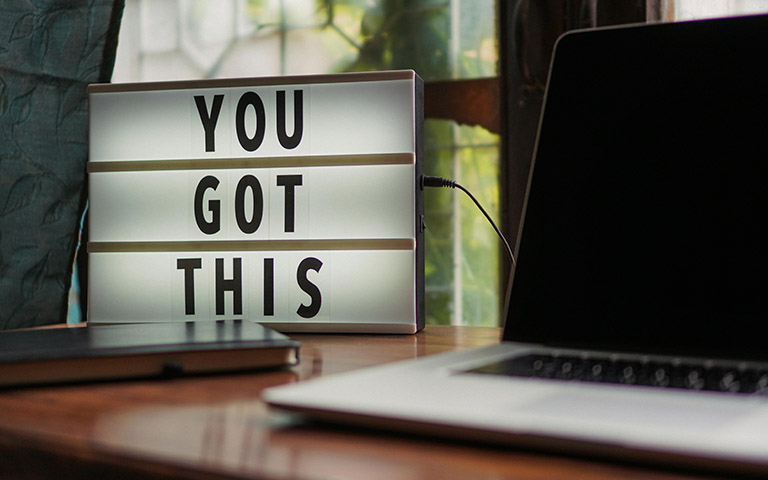 A sign that says "You Got This" next to a laptop. 