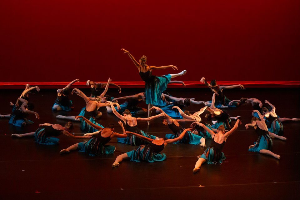 A group of dancers performs energetically on stage, showcasing their synchronized movements and vibrant costumes.