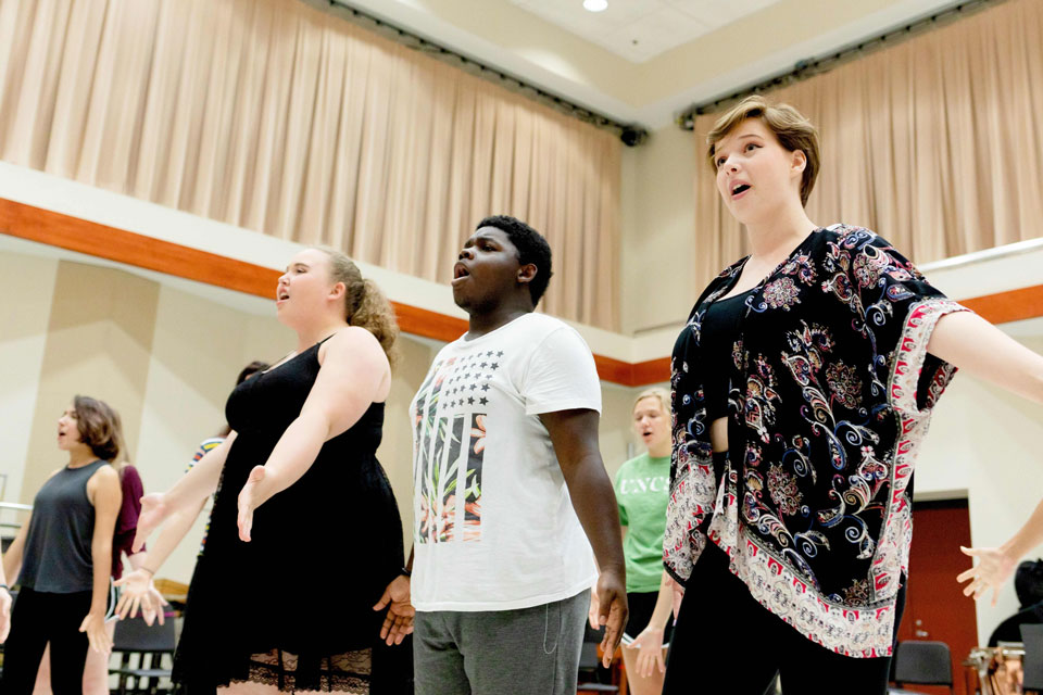 A group of people standing in a room, arms outstretched, expressing joy and unity.